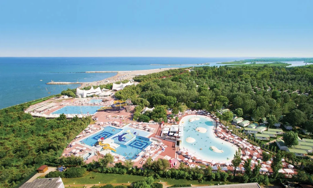 Aerial view of pools bordered by loungers near forested coastline at Isamar