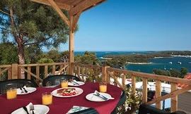 A table set with breakfast overlooking a scenic coastal view and surrounded by trees at Orsera