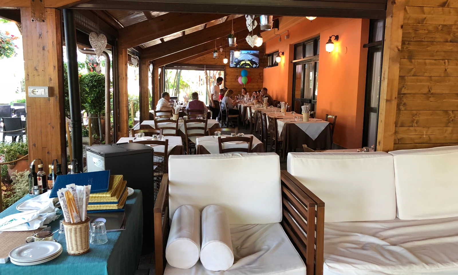 Restaurant with wooden interior, people dining at tables, organized utensils on a side table at Centro Vacanze San Marino