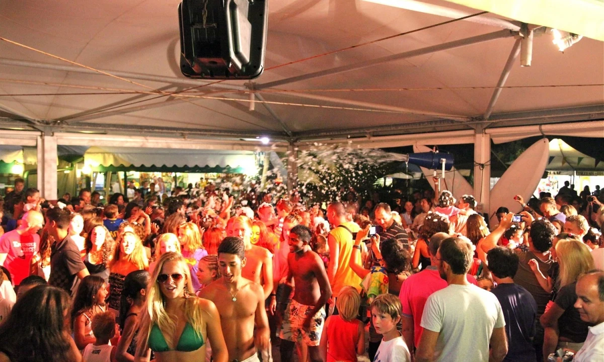 Large crowd enjoying a foam party under a spacious tent at Isamar