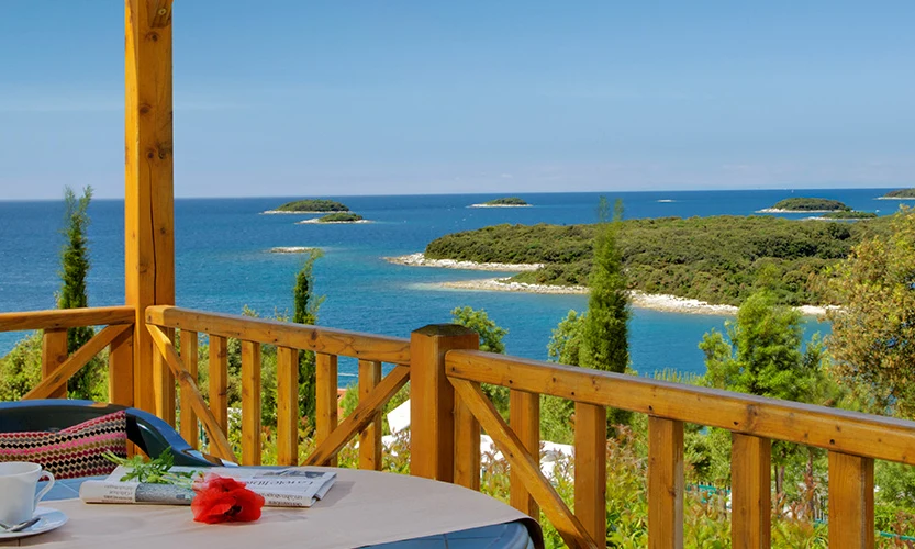 A table with a coffee cup and flower on a balcony overlooking the sea and small islands at Orsera