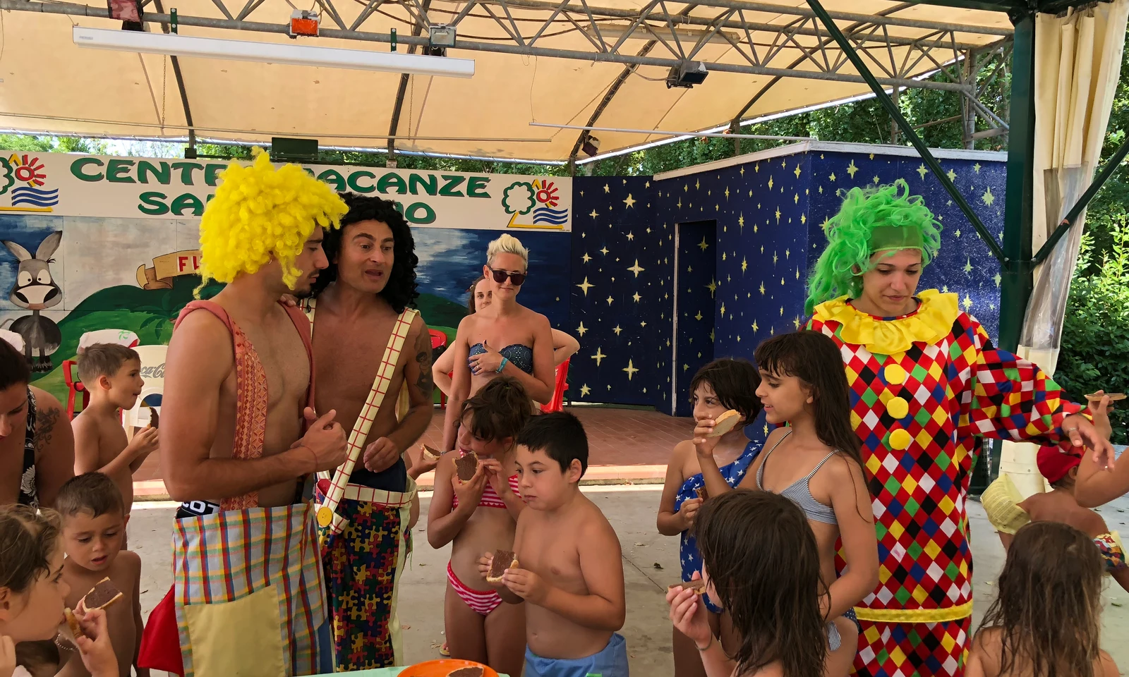 Two clowns entertain children eating snacks under a pavilion at Centro Vacanze San Marino