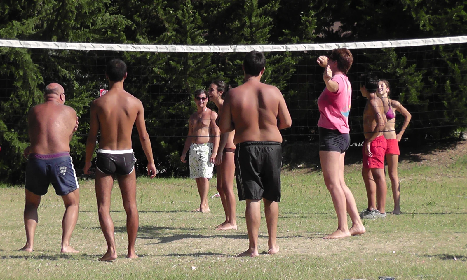 People play beach volleyball on a grassy field surrounded by trees at Centro Vacanze San Marino