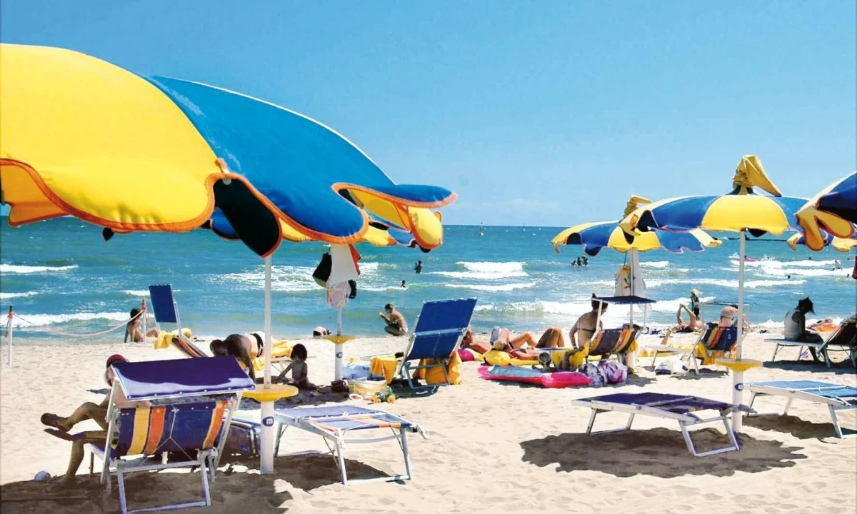 Colorful beach umbrellas and lounge chairs sheltering people relaxing on a sunny, sandy beach near a blue ocean at Isamar