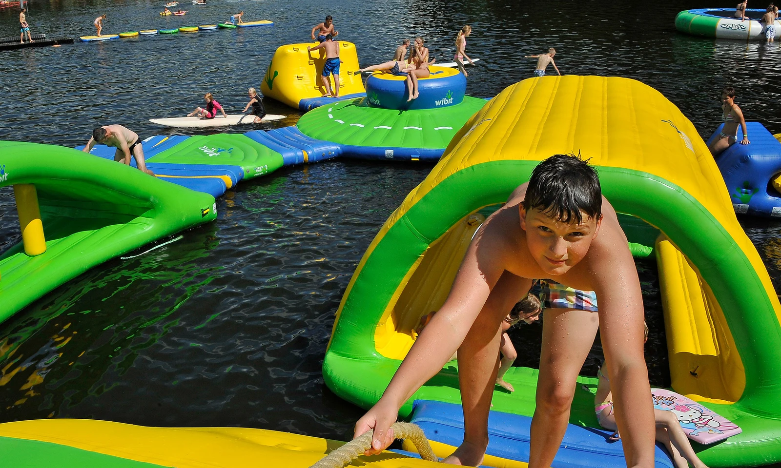 Child climbs inflatable structure, surrounded by others playing, on water at Natterer See