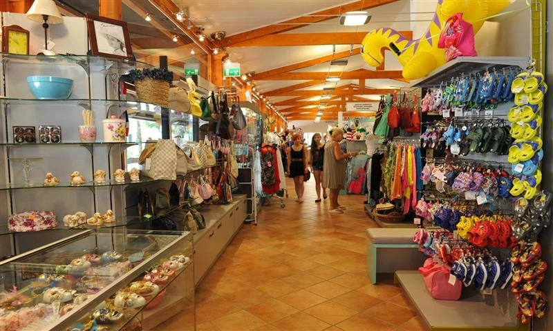 Store selling various beach goods with customers browsing the aisles, surrounded by colorful items and wooden beams overhead at Isamar