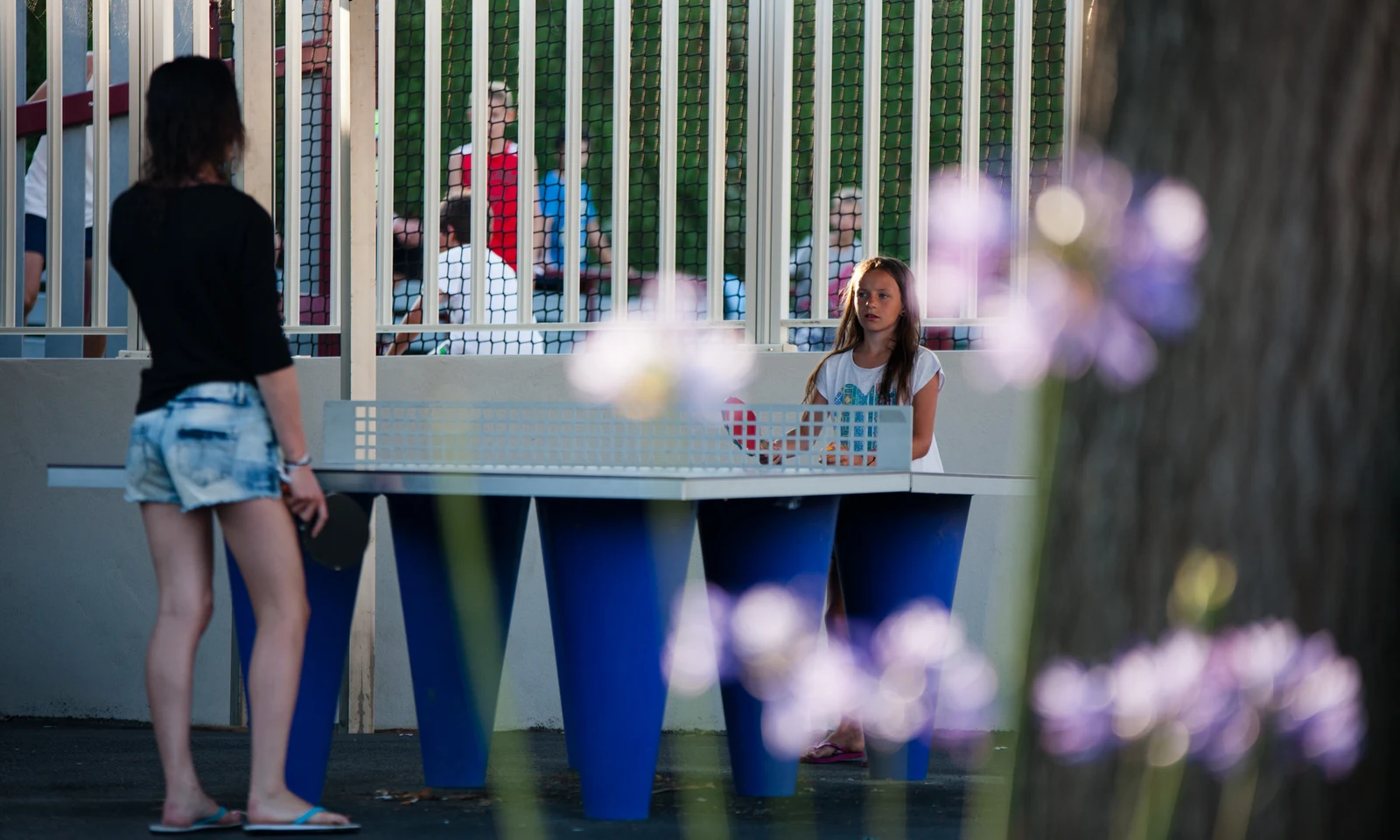 Two people play table tennis outside, surrounded by flowers and a fence at Ur-Onéa