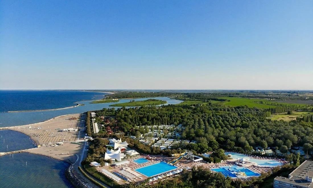 Beach, pools, and buildings beside a forest, next to the ocean at Isamar