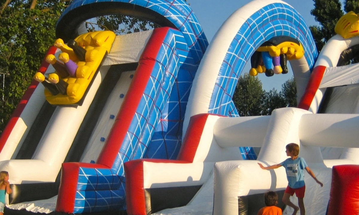 Inflatable slide with children playing in a wooded outdoor setting at Isamar