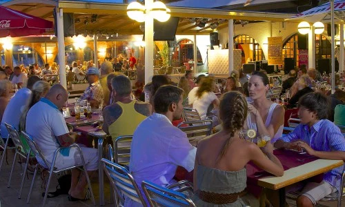 People sitting and chatting at an outdoor cafe with lively evening atmosphere at Bon Repos