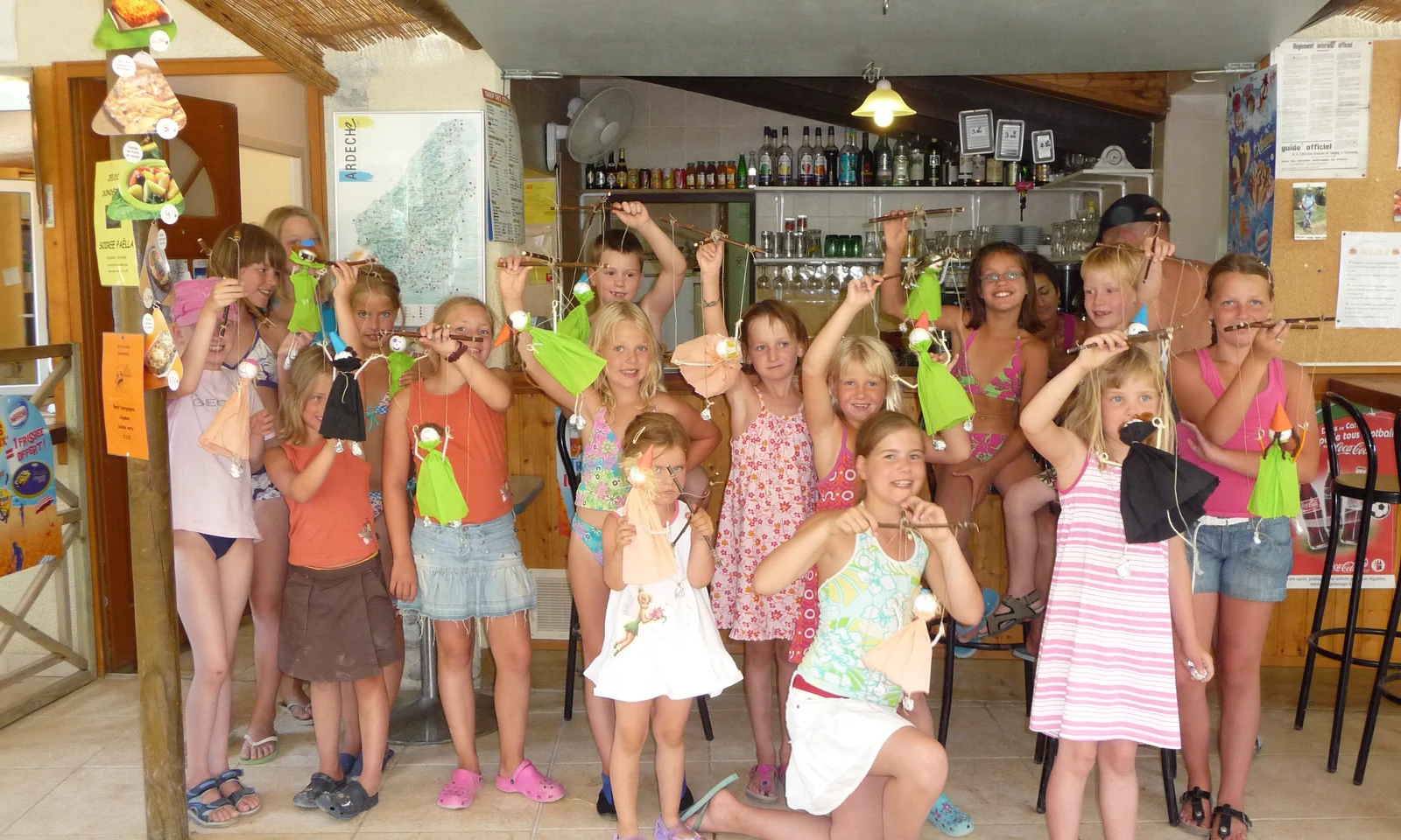 Children holding crafts and posing together in a bar area at Les Arches