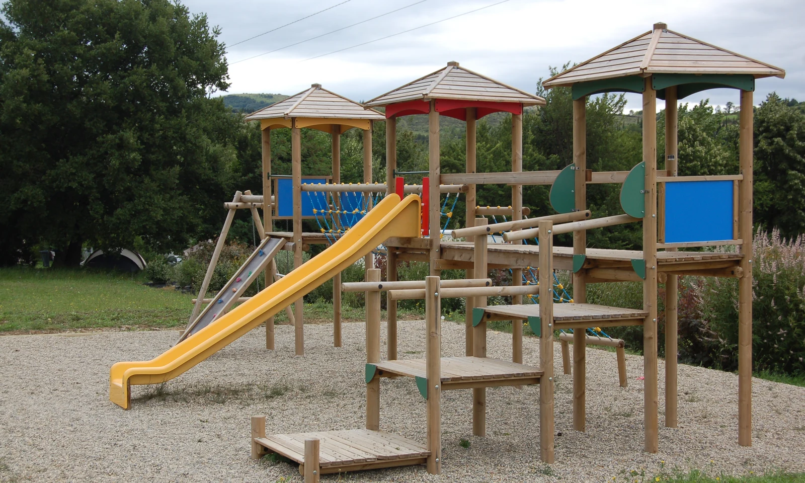 Wooden playground structure with slides and climbing areas in a grassy, park-like setting at Les Arches