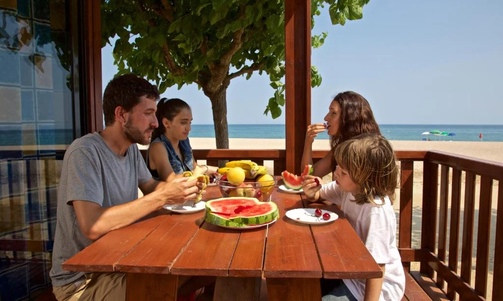 Family eating fruit at a wooden table by the beach with ocean view at Bon Repos