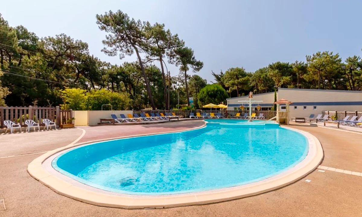 Swimming pool surrounded by lounge chairs and trees at Camping 2 Plages & Océan Village Corsaire