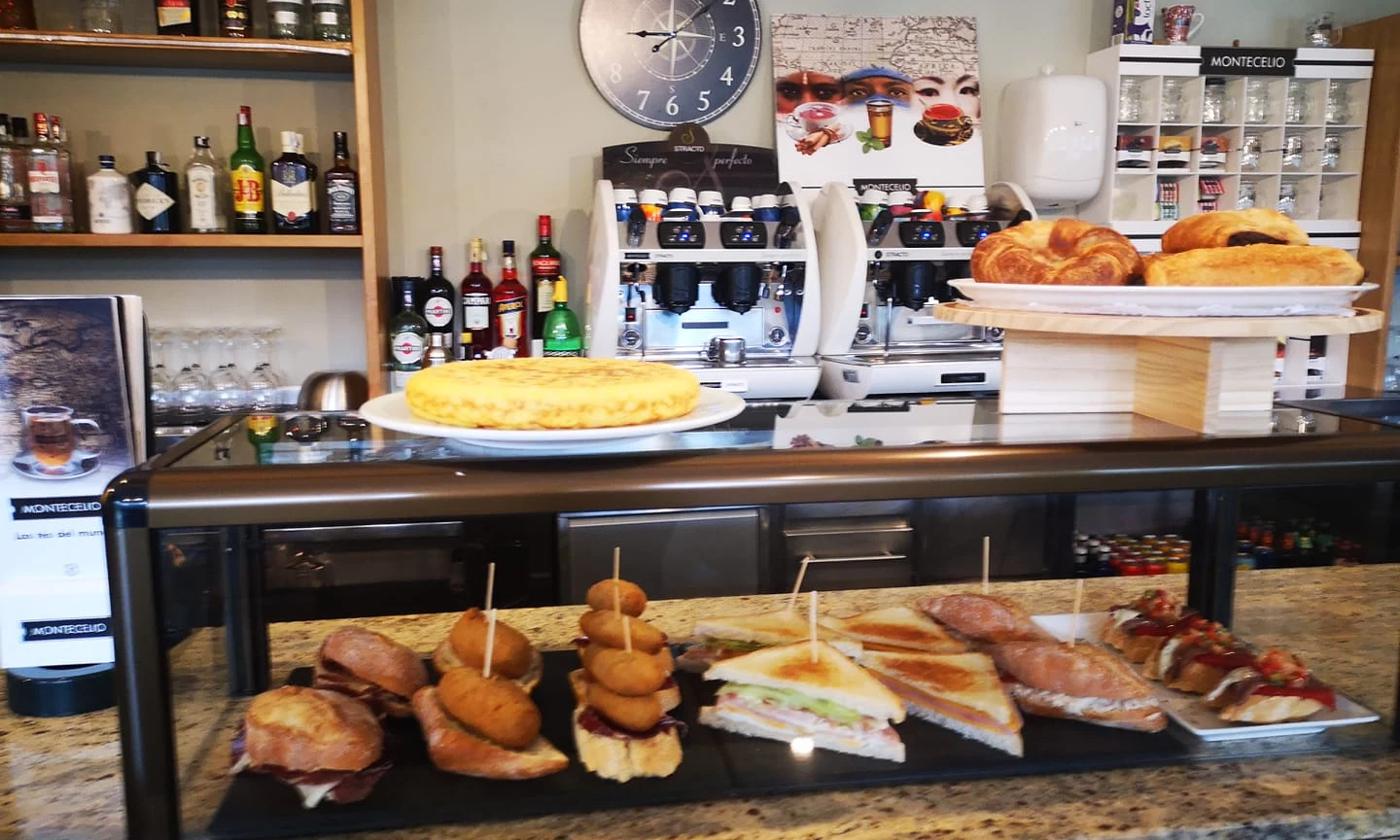 Pastries and sandwiches displayed on a countertop; bottles and coffee machines in the background at Etxarri