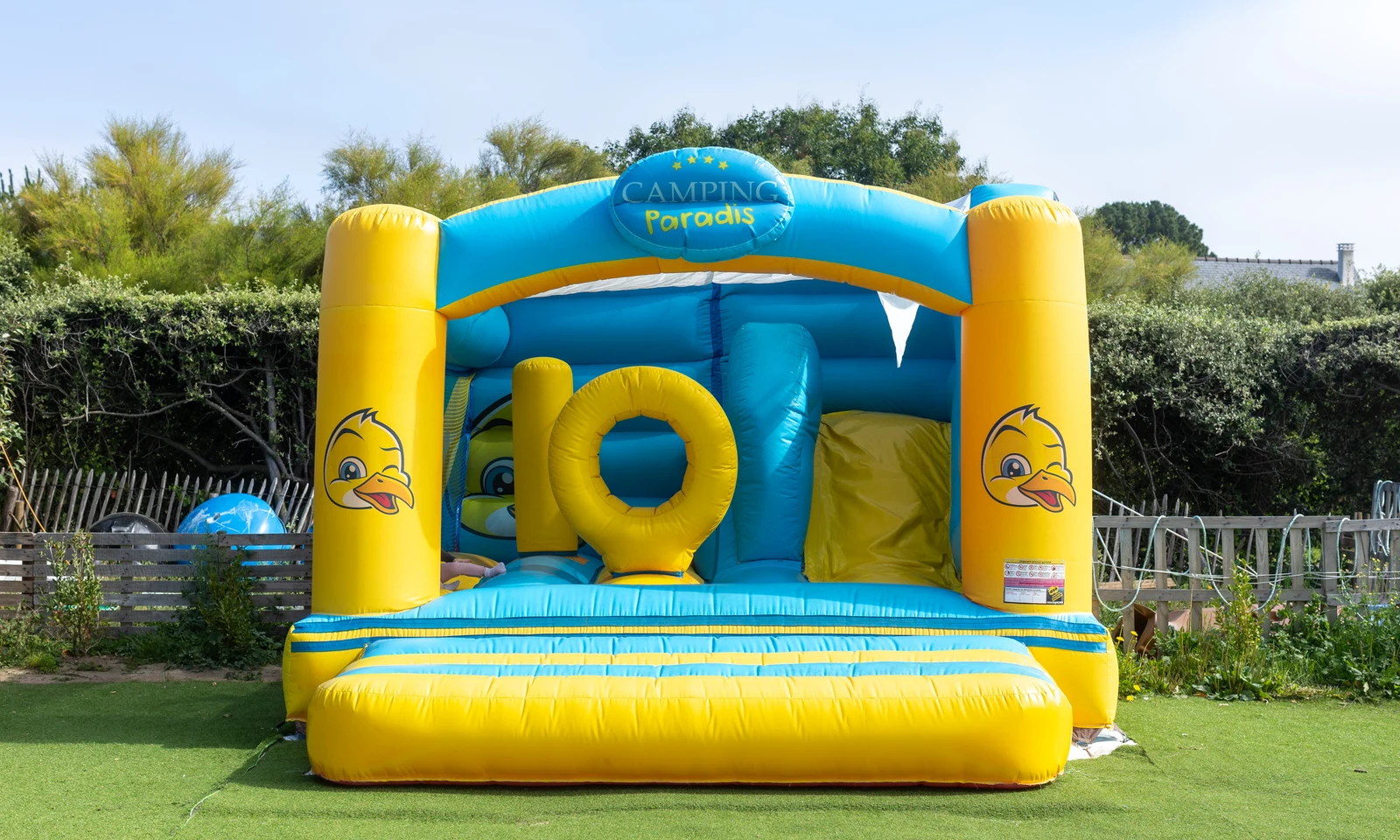 Inflatable bounce house decorated in yellow and blue, duck faces visible, set on a grassy area at La Pointe de Roscoff