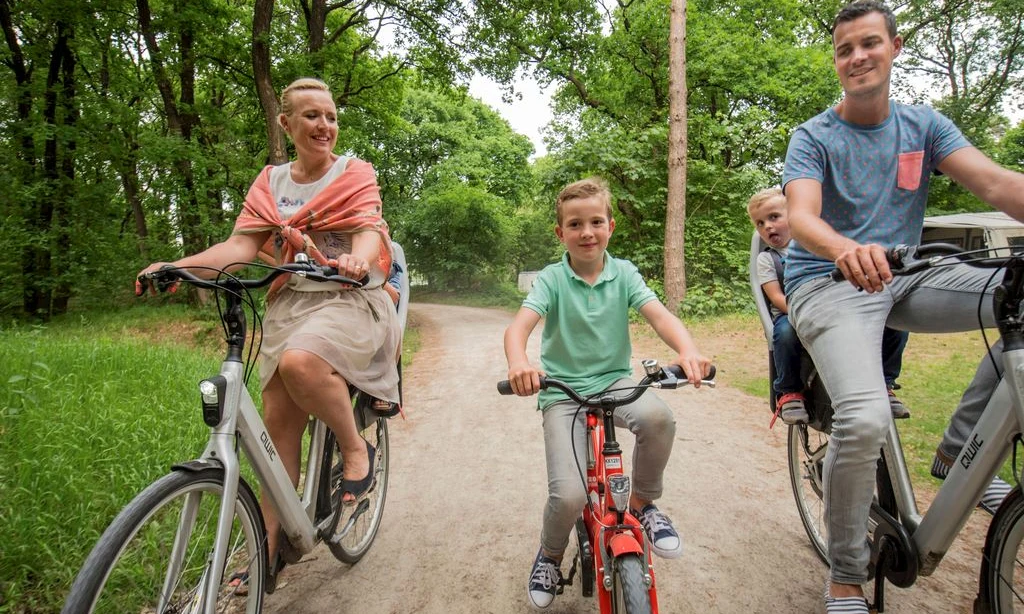 Family riding bikes along a forest path, enjoying the outdoors together at Landal Rabbit Hill