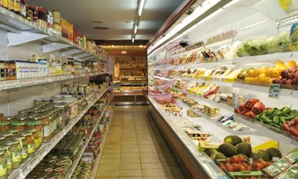 Shelves stocked with various food and grocery items, lining a brightly lit aisle in a supermarket at Bon Repos