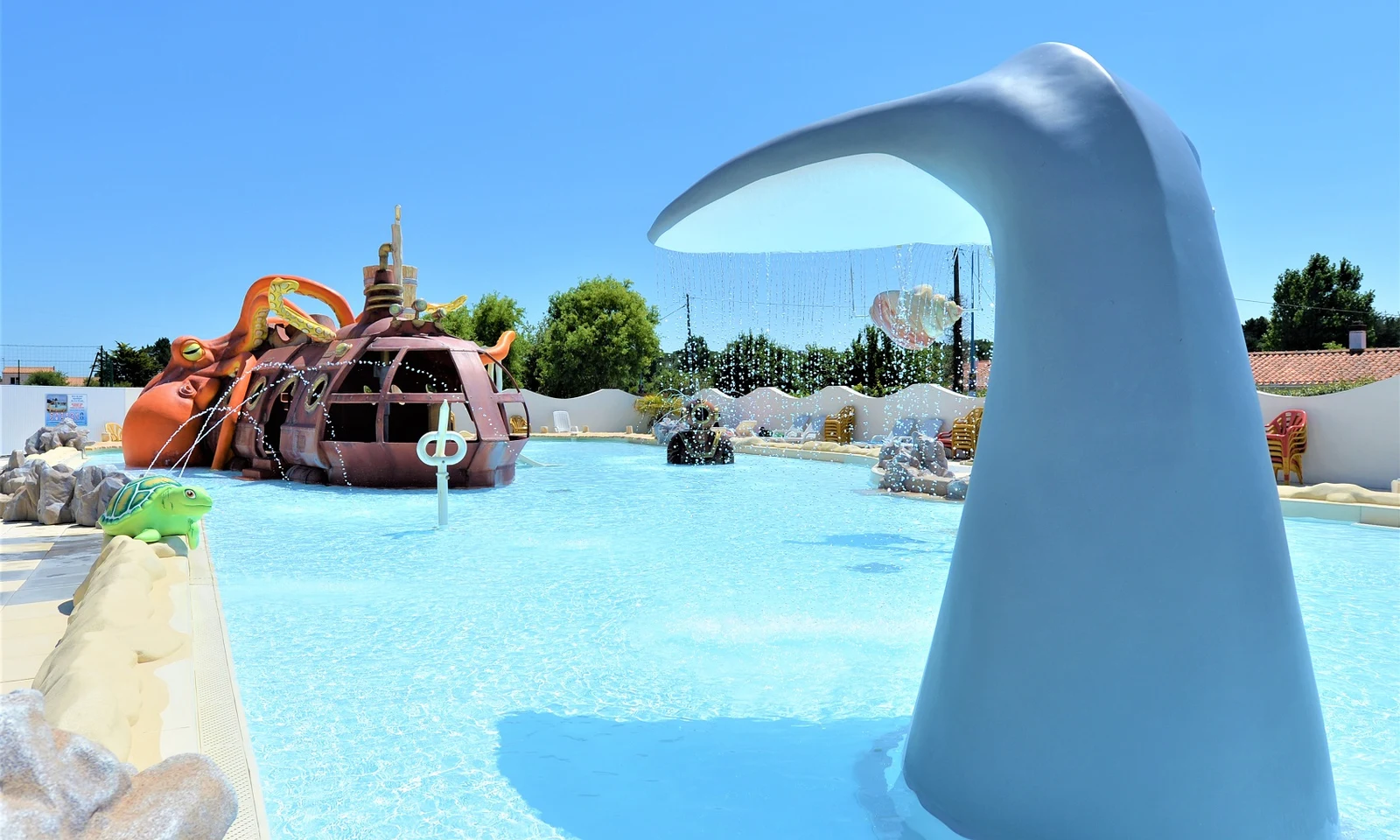 Colorful water playground featuring a large octopus structure in a shallow pool surrounded by trees and buildings at Les Aventuriers de la Calypso