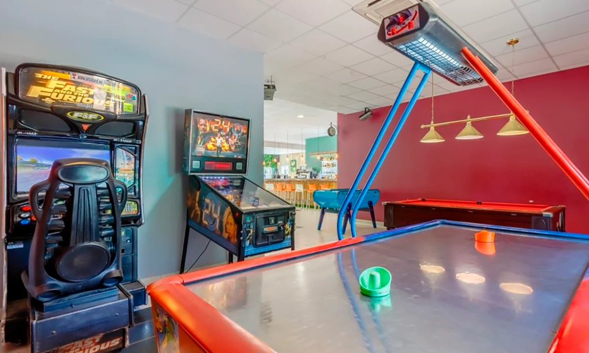 Arcade machines, air hockey table, and pool table in a recreational room; bright and spacious setup at Camping 2 Plages & Océan Village Corsaire