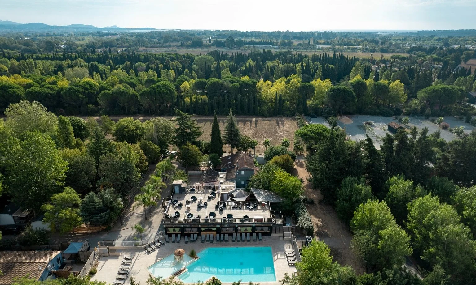 Aerial view of a swimming pool surrounded by lounge chairs and trees at La Barque