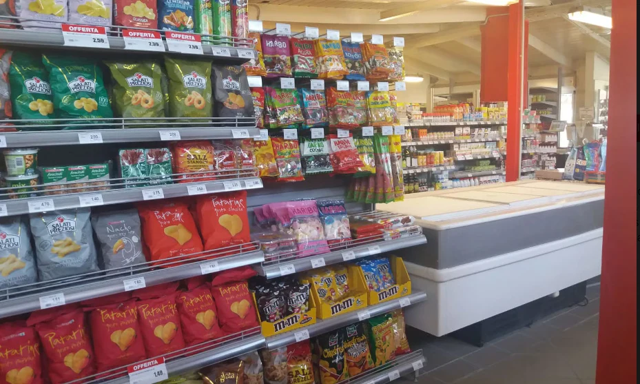 Shelves stocked with various snacks and candy in a brightly lit convenience store at International Riccione Family Camping Village