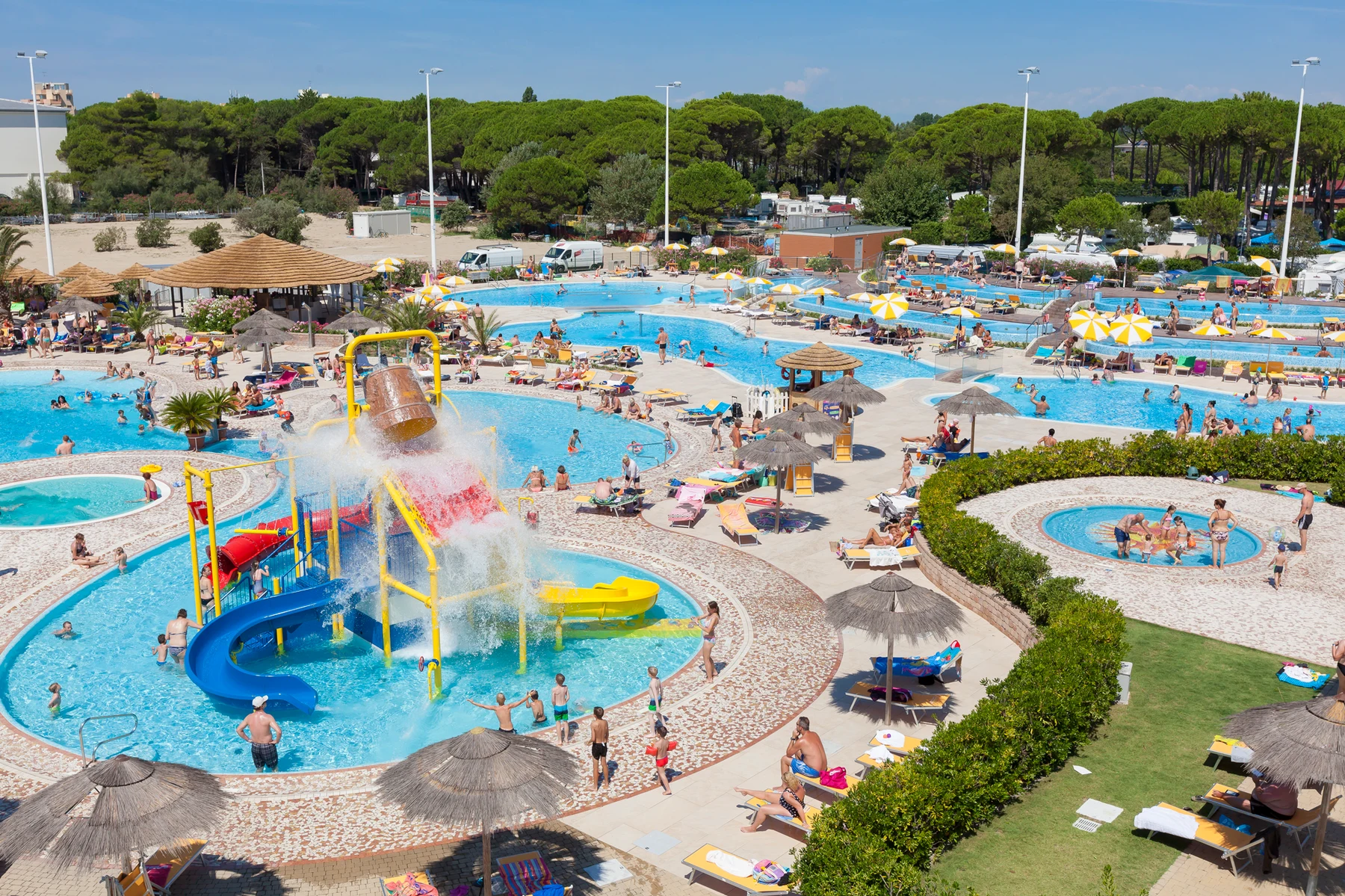 Children playing on water slides and splash area surrounded by multiple pools and lounging adults at Internazionale