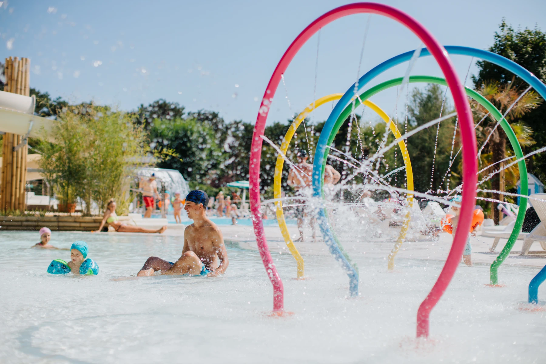 Children playing in a shallow water pool with colorful water arches at Sabbiadoro