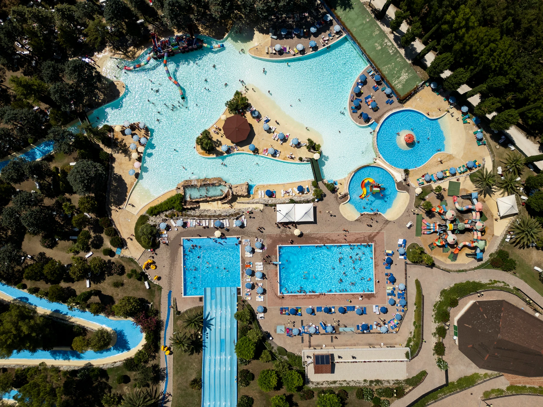 Waterpark with multiple pools and slides, surrounded by sunbathing areas and trees at Centro Vacanze Verde Azzurro