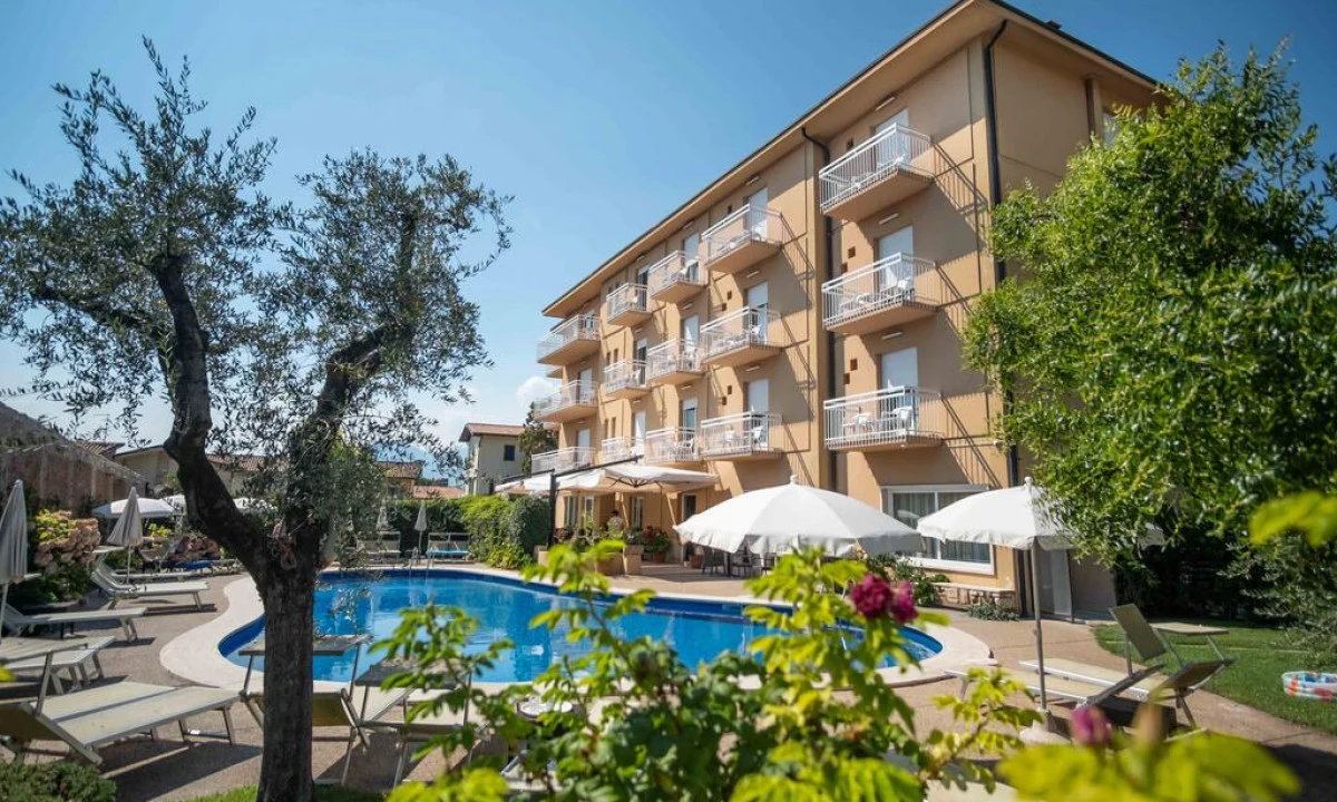 Four-story hotel building overlooking a swimming pool surrounded by trees and lounge chairs at Hotel Romeo