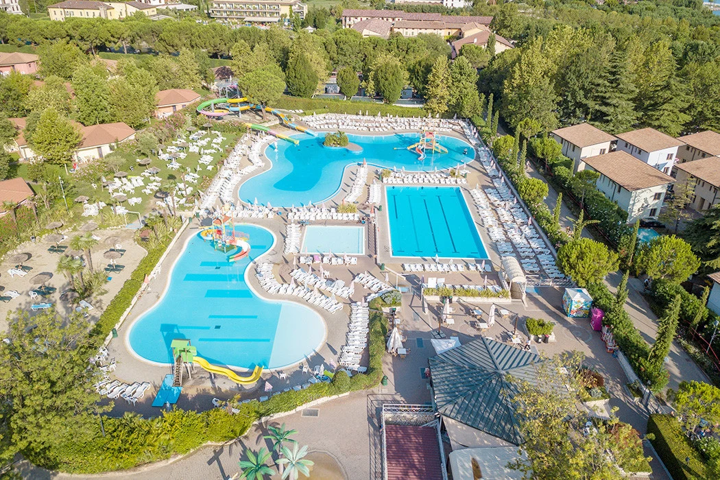 Swimming pools with slides surrounded by lounge chairs and trees at Bella Italia