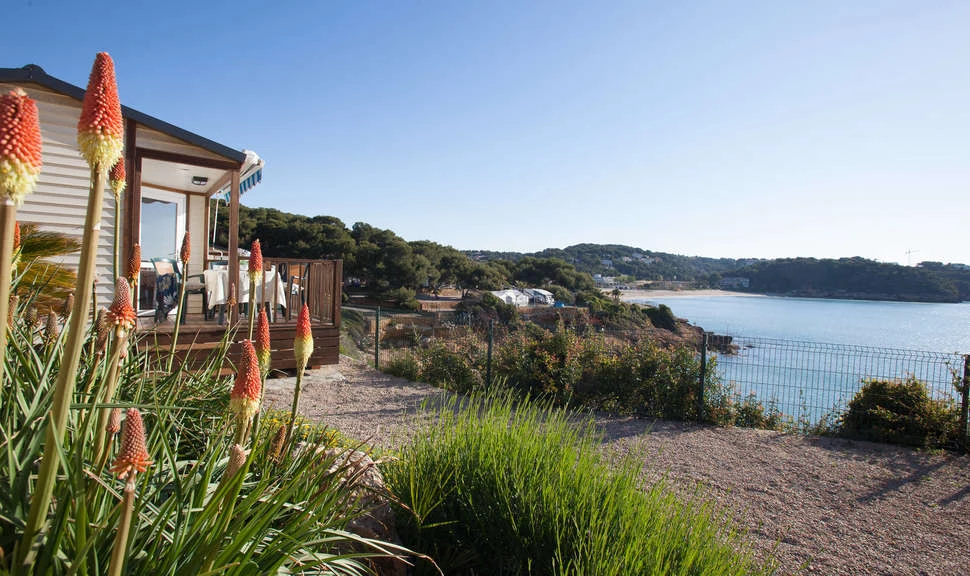 Wooden deck with chairs overlooking a coastal view surrounded by greenery and flowers at Torre de la Mora