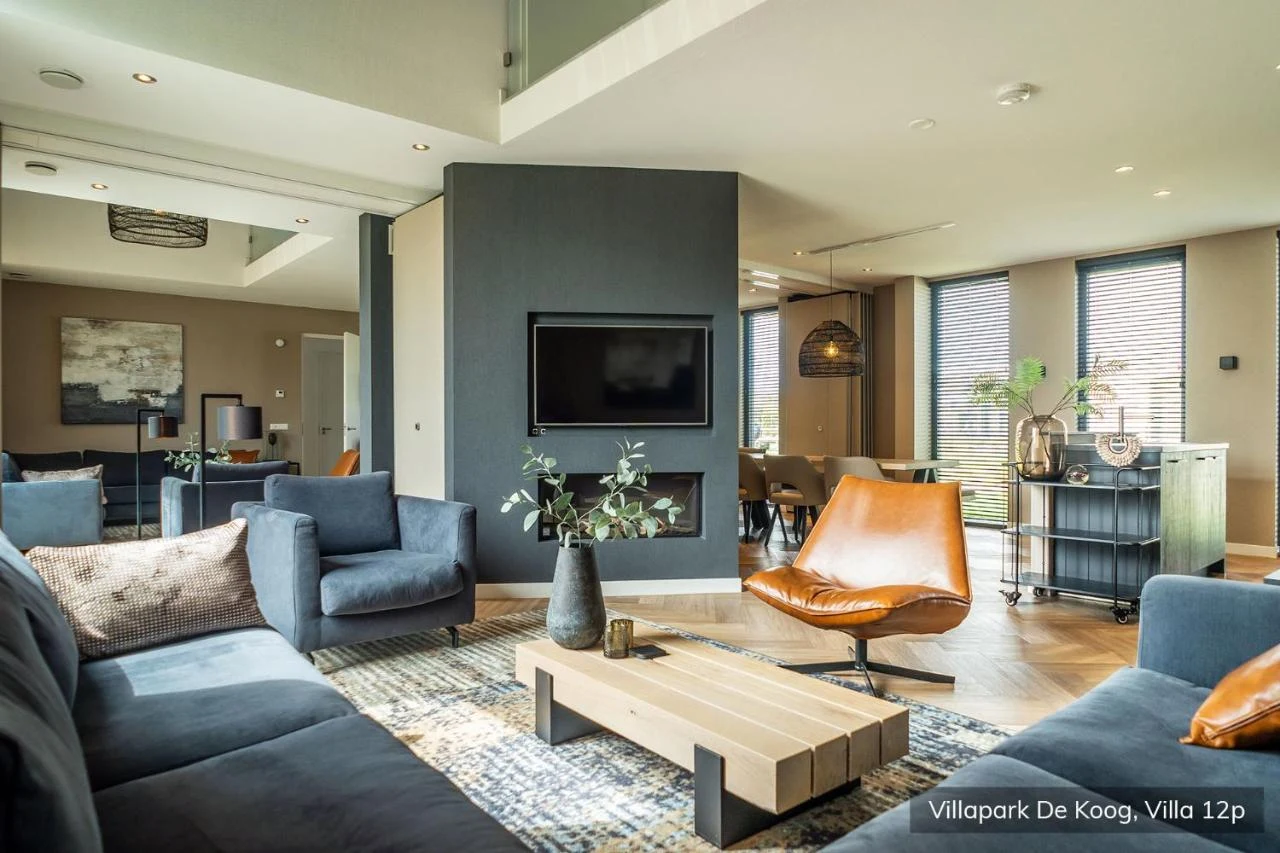 Modern living room with cozy seating, a wooden coffee table, and a wall-mounted TV in a bright, stylish home at Villapark de Koog