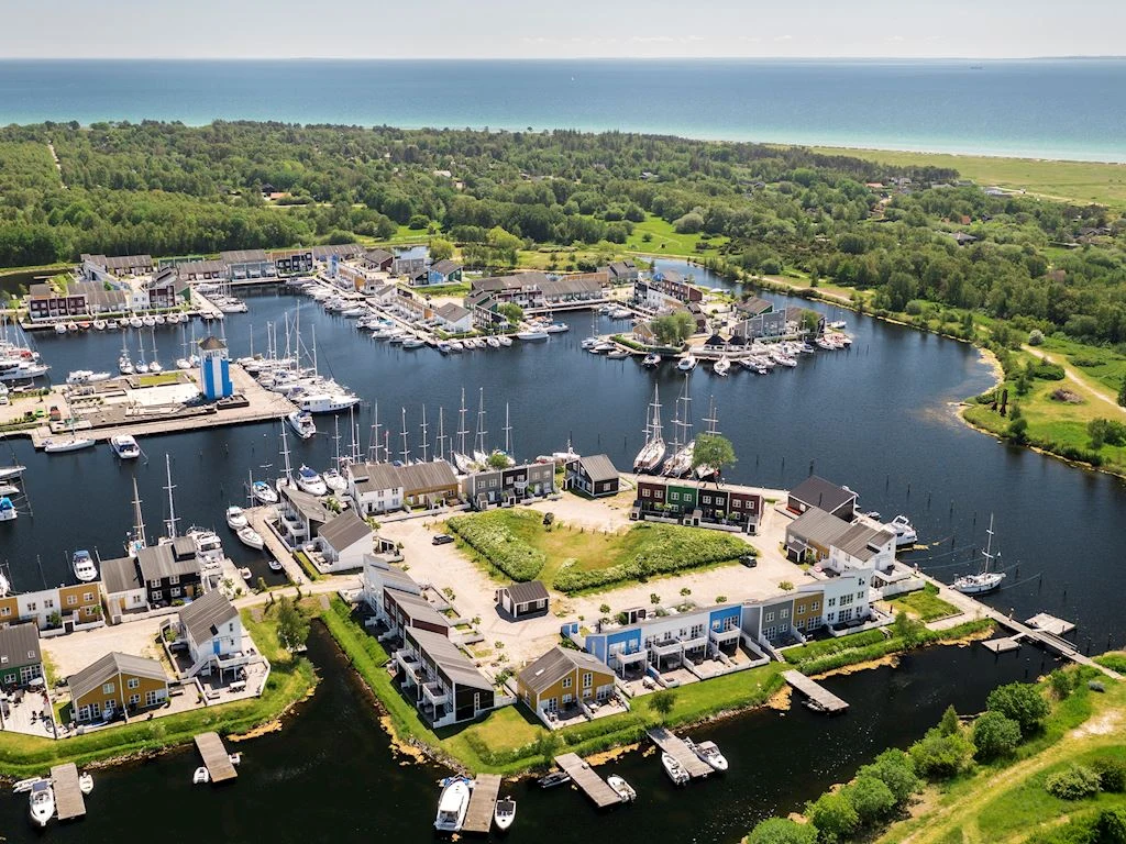 Boats anchored in a marina surrounded by residential buildings, set near a forested area next to the ocean at Landal Ebeltoft
