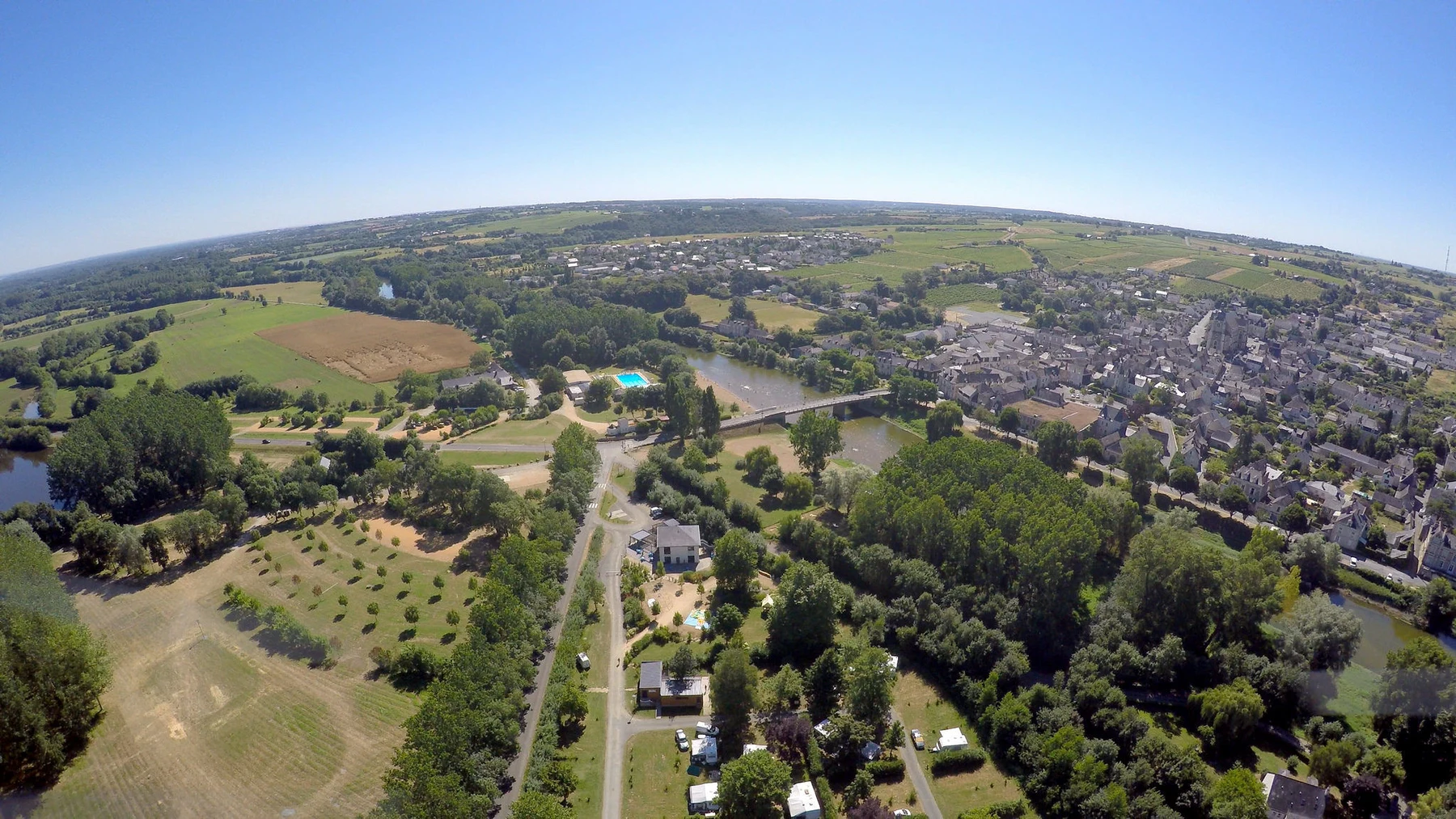 Aerial view of a small town with a river and green fields, surrounded by countryside at Seasonova Les Plages de Loire
