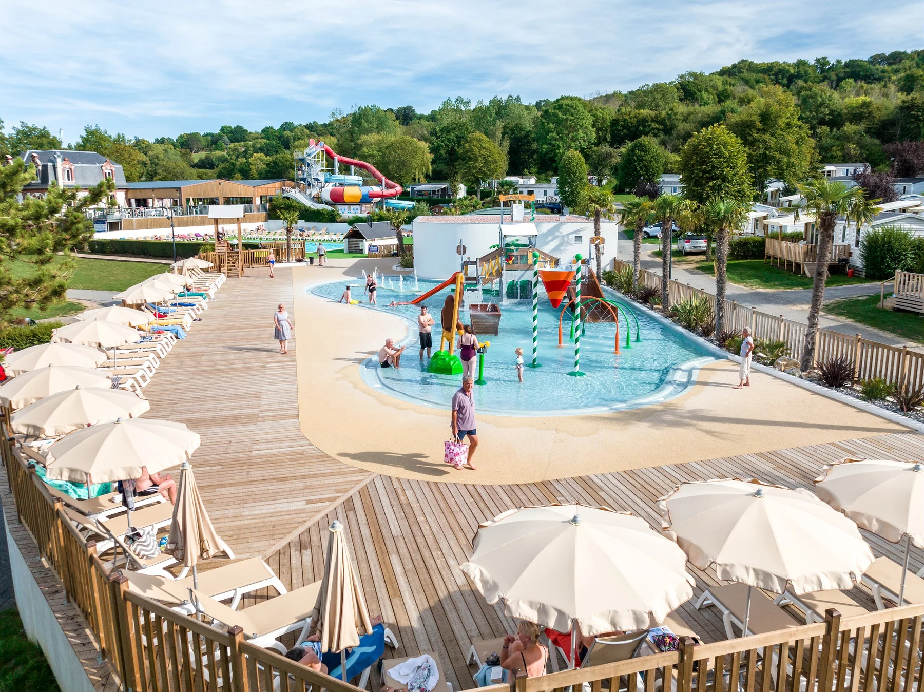 Children playing in a splash pool while others relax on lounge chairs near umbrellas at Marvilla Parks La Vallée
