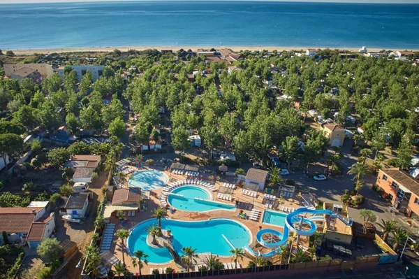 Large swimming pool complex with slides surrounded by trees and camping facilities near a beach at Les Mediterranées Nouvelle Floride