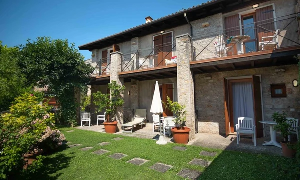 Two-story stone cottage with outdoor seating, surrounded by greenery and gardens at Hotel Romeo
