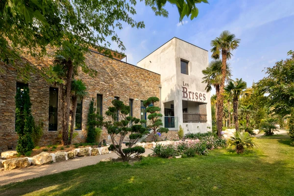 Stone building surrounded by palm trees and shrubs, blue sky at Sequoia Parc