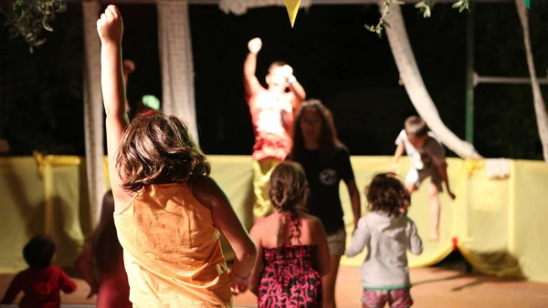 Children dancing to a performer on stage at night in an outdoor setting at Villenpark Sanghen