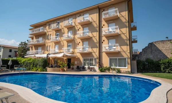 Building with balconies overlooking a swimming pool, surrounded by lounge chairs and greenery at Hotel Romeo