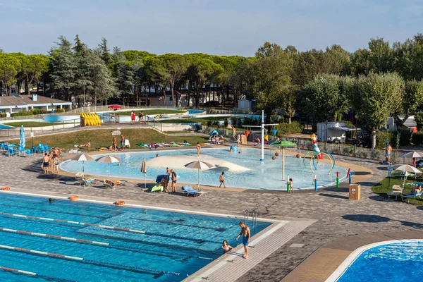 Swimming pools with people enjoying water activities, surrounded by trees and recreational areas at Marina Julia Family Camping Village
