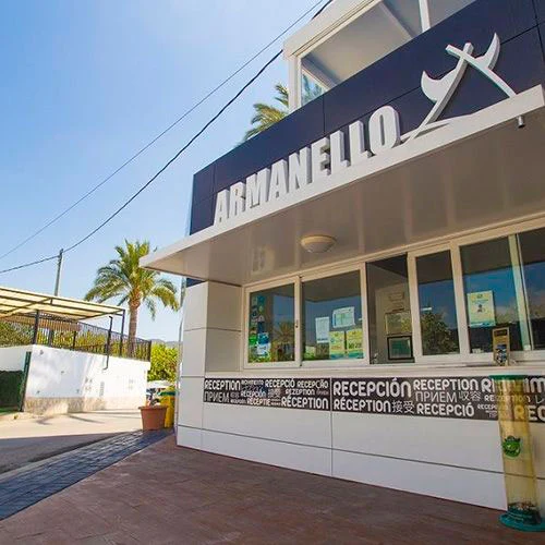 Reception building with a modern design, displaying multiple languages palm trees and clear sky background at Armanello