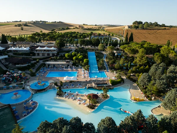 Large swimming pool complex with slides and lounge areas, surrounded by lush greenery and fields at Centro Vacanze Verde Azzurro