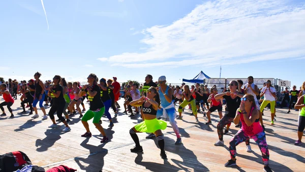 People exercising energetically on a wooden platform outdoors, under a clear blue sky at Savoy Beach Hotel & Thermal Spa
