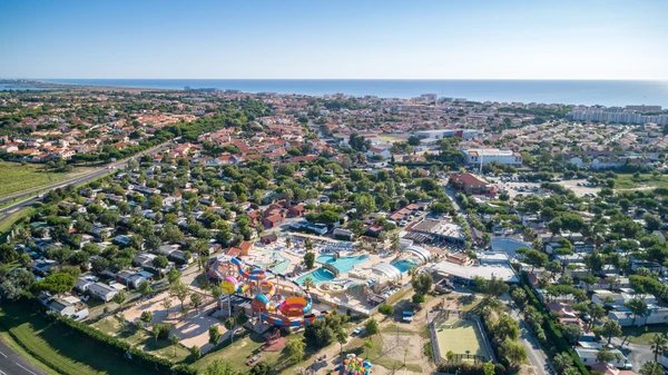 Aerial view of a large camping site with water park attractions within a densely populated residential area near the ocean at Marvilla Parks Le Soleil de la Mediterranee