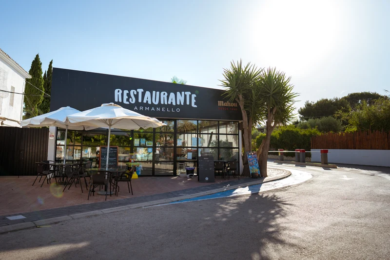 Restaurant with outdoor seating under umbrellas, situated beside a curving road and surrounded by greenery at Armanello