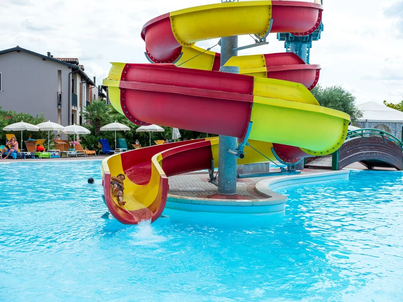 Colorful water slide ending in a swimming pool, with sun loungers and umbrellas nearby at Residence Eden
